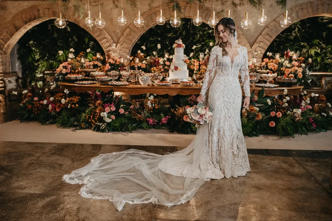 Noiva de vestido branco segurando o buquê.