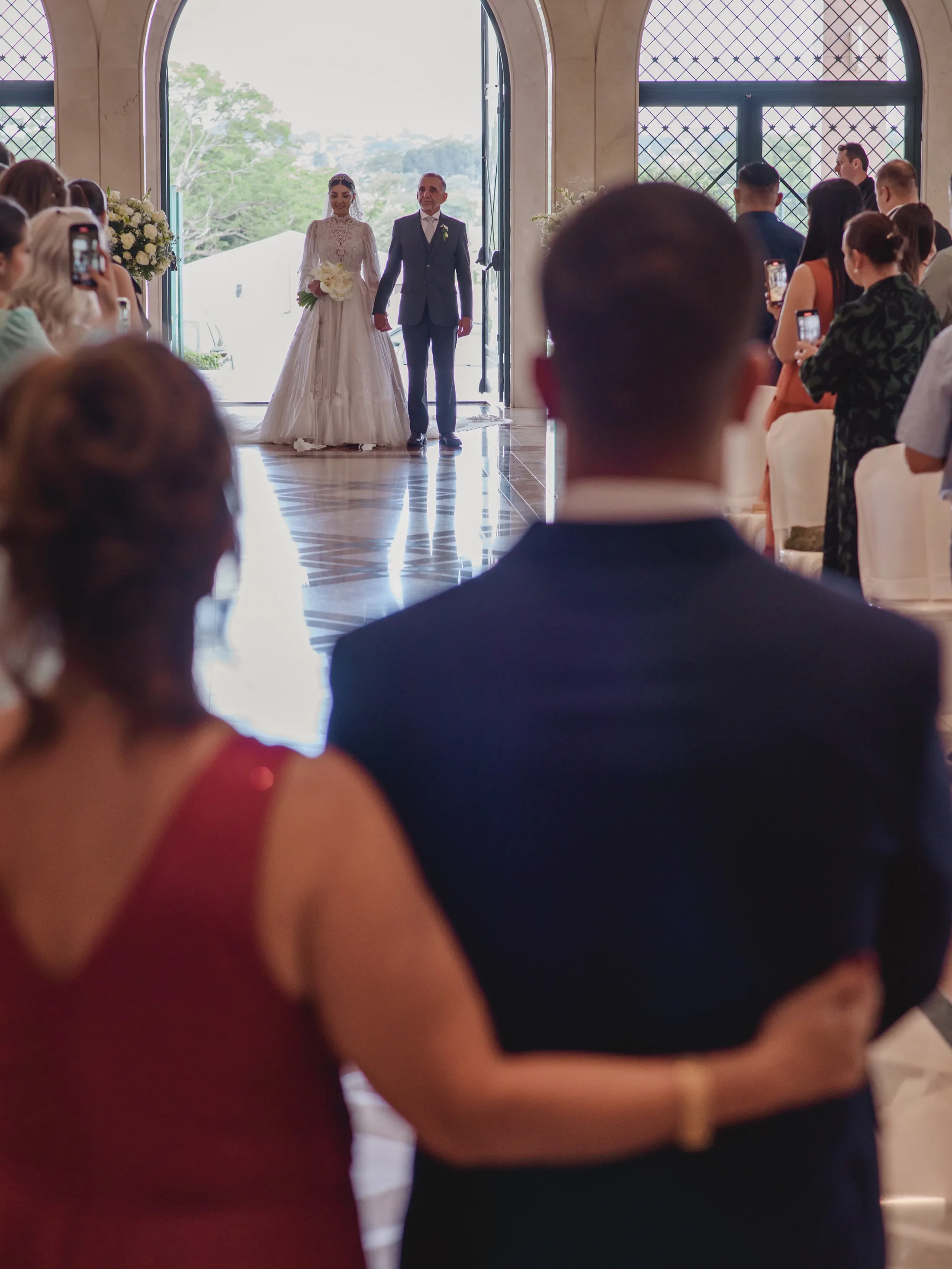 Noiva acompanhada por um homem na entrada da igreja.