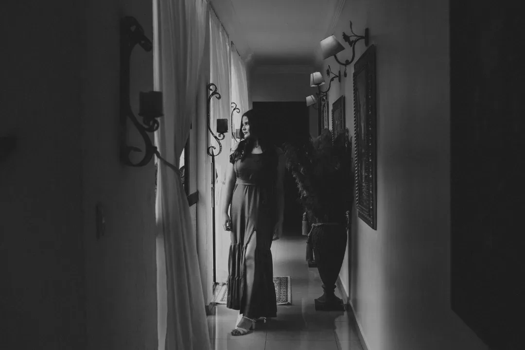 Jovem de vestido em um ambiente interno, fotografada em preto e branco.