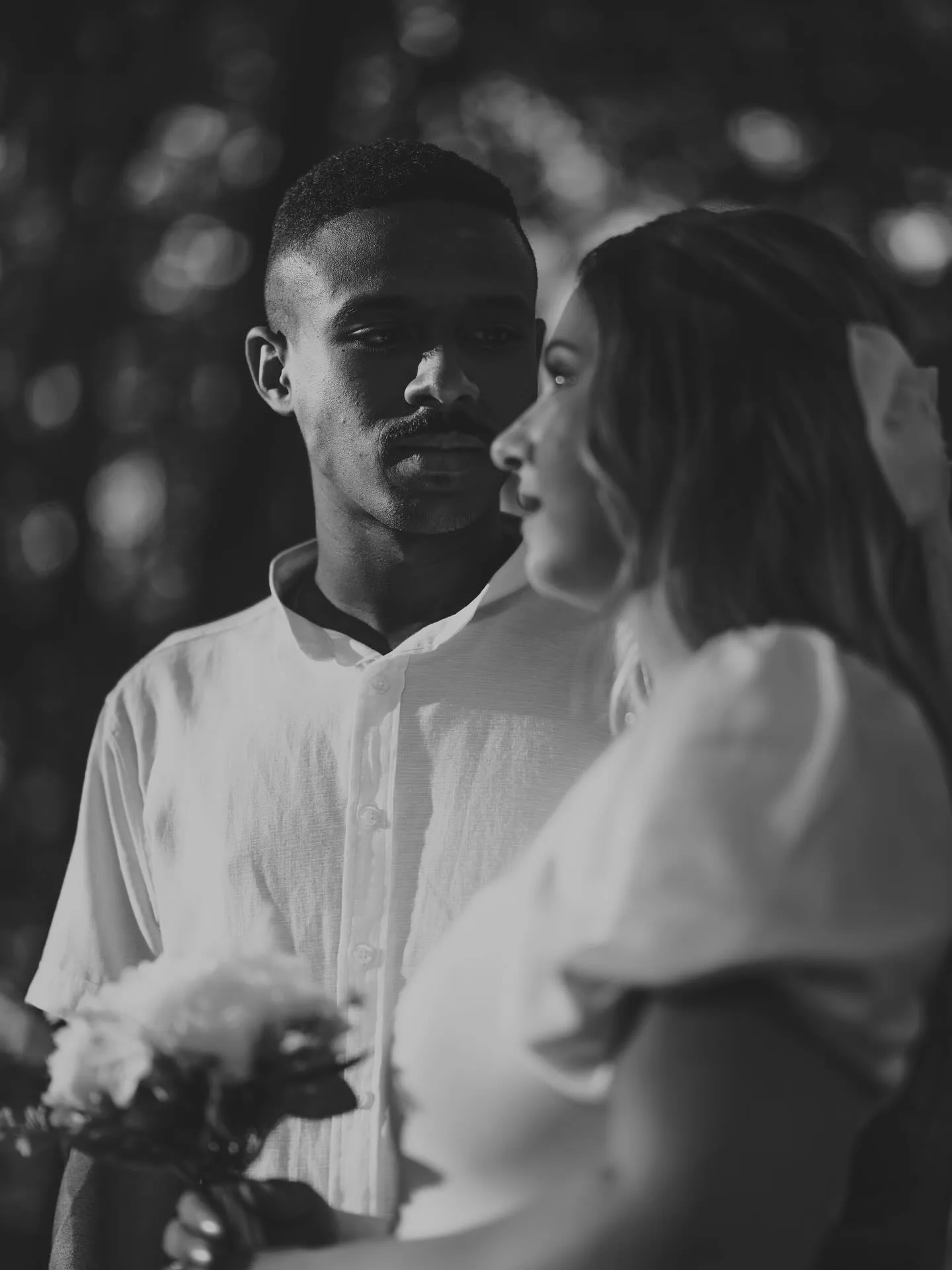 Casal abraçado em um ambiente escuro, em preto e branco.