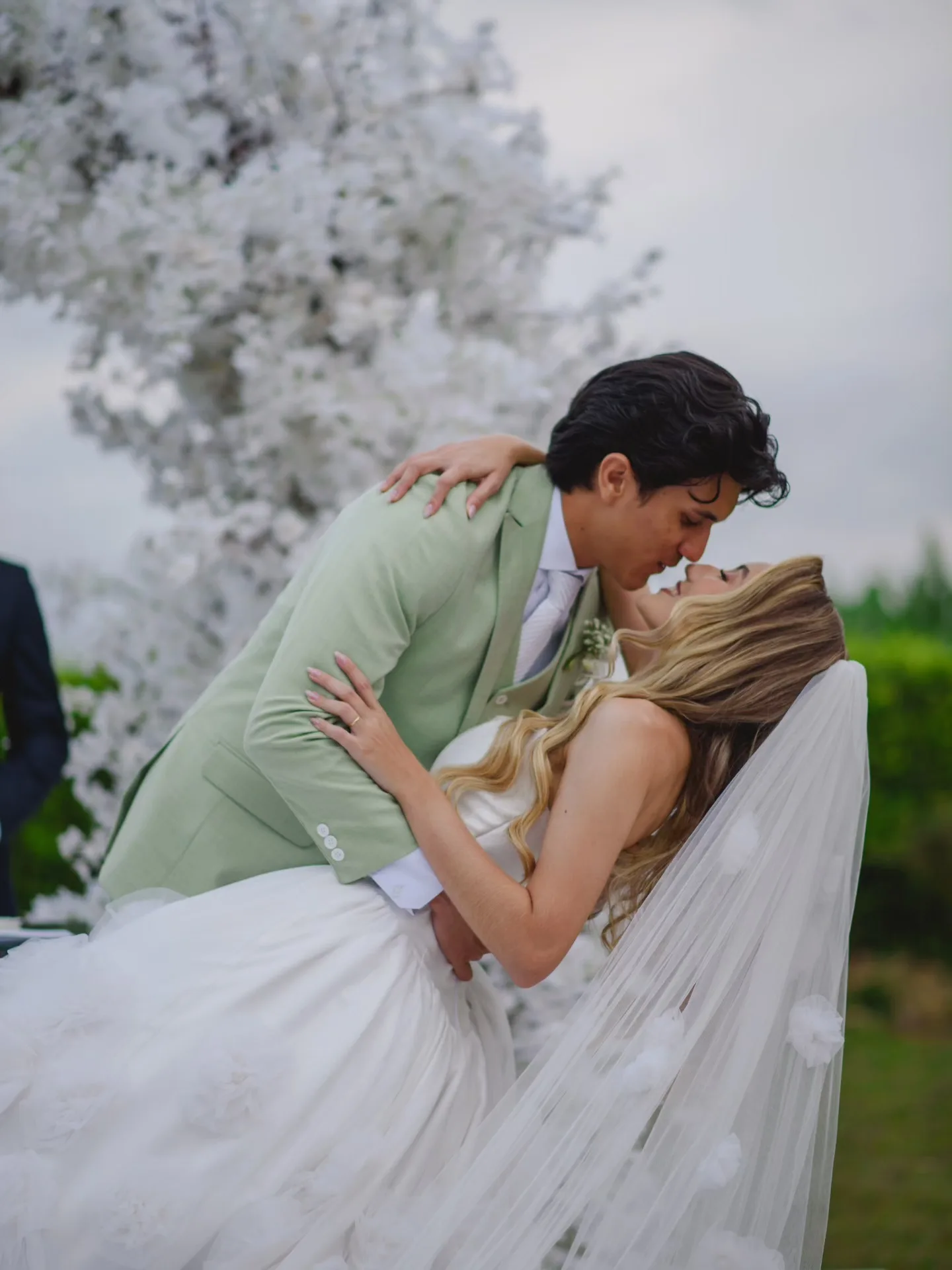 Noivo de terno verde beijando a noiva.
