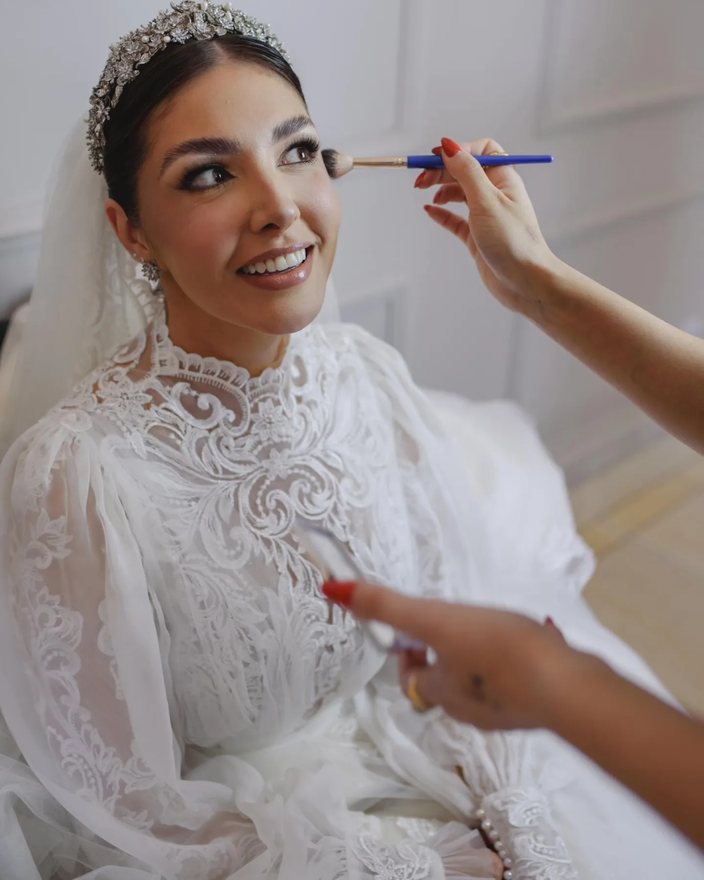 Noiva sorrindo enquanto recebe maquiagem.