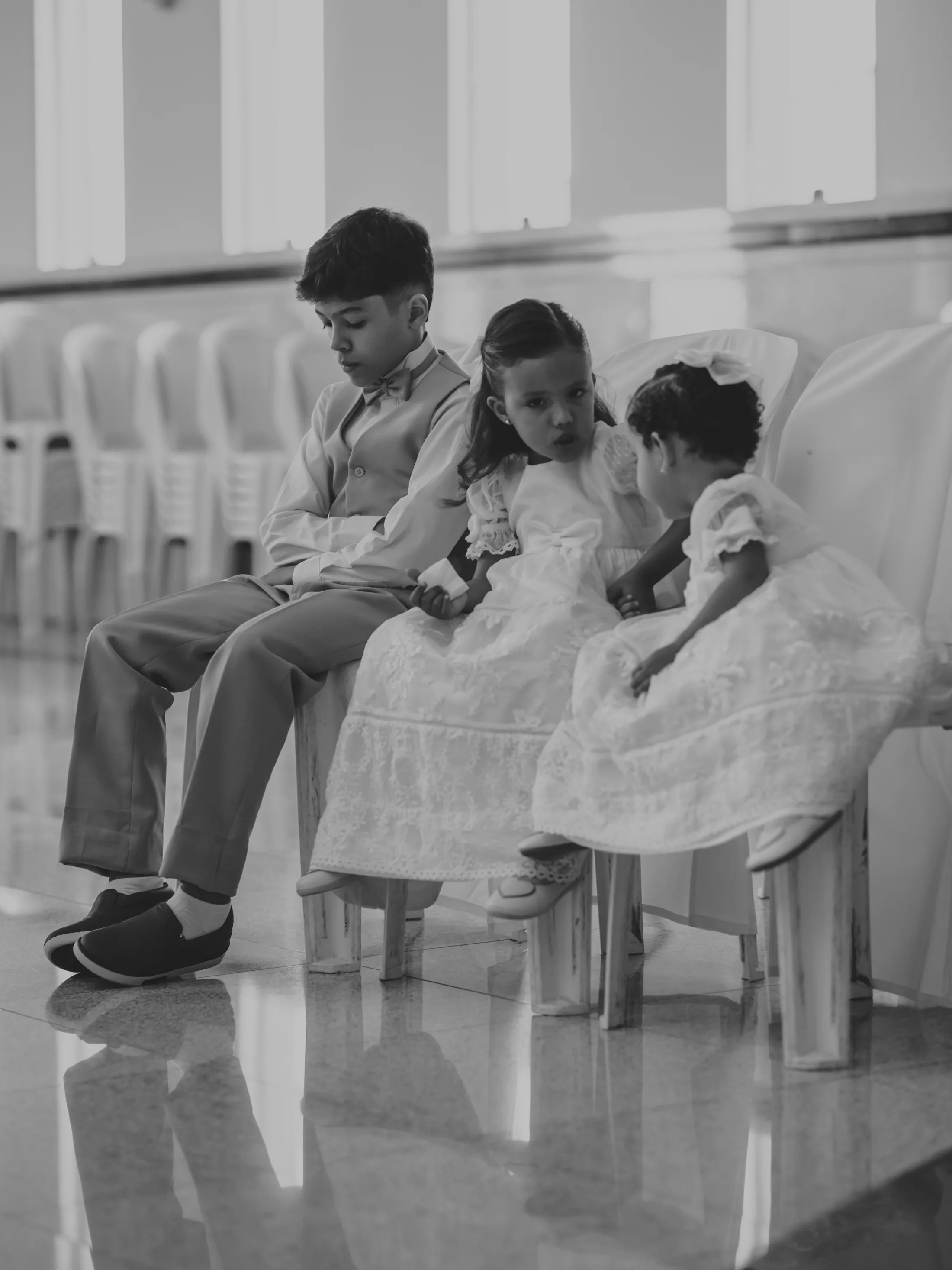 Convidados sentados em bancos de igreja, em preto e branco.