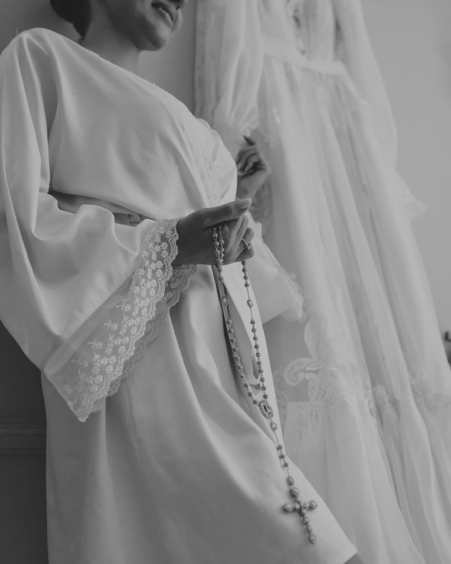 Detalhe das mãos ajustando o robe da noiva, em preto e branco.