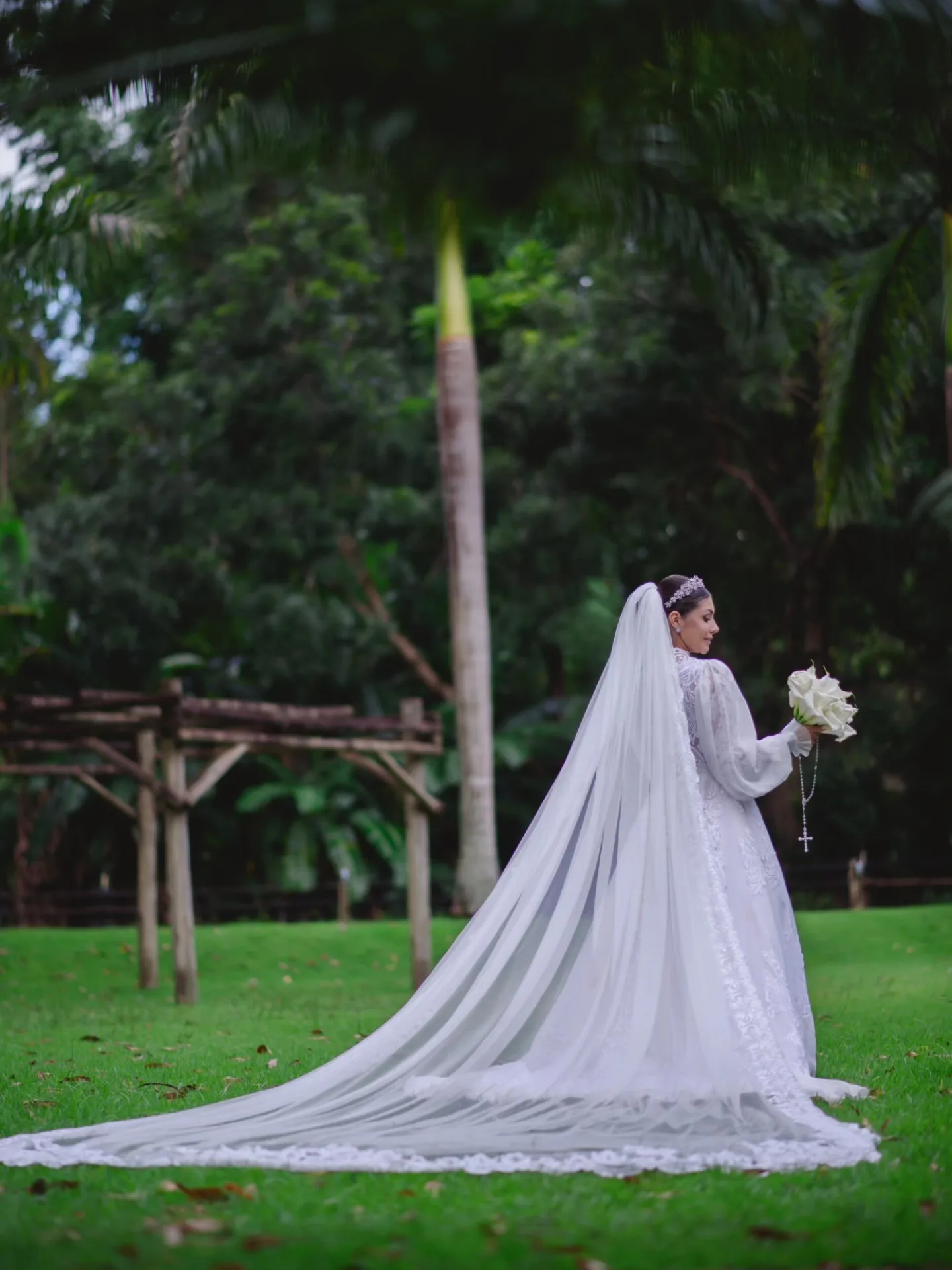 Noiva de vestido longo ao lado do noivo em um jardim.
