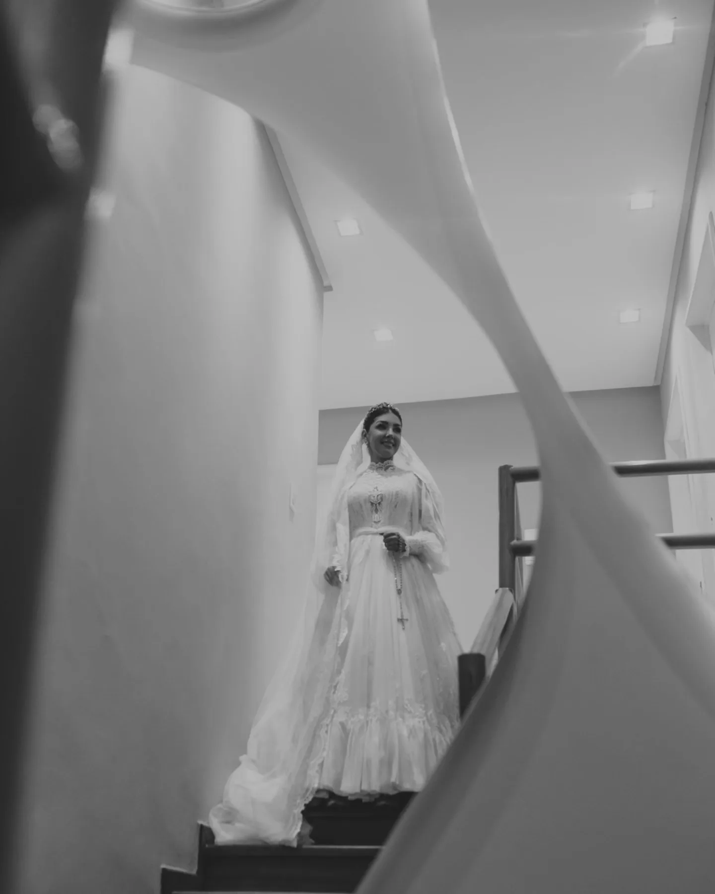 Noiva vista através do véu, em fotografia em preto e branco.