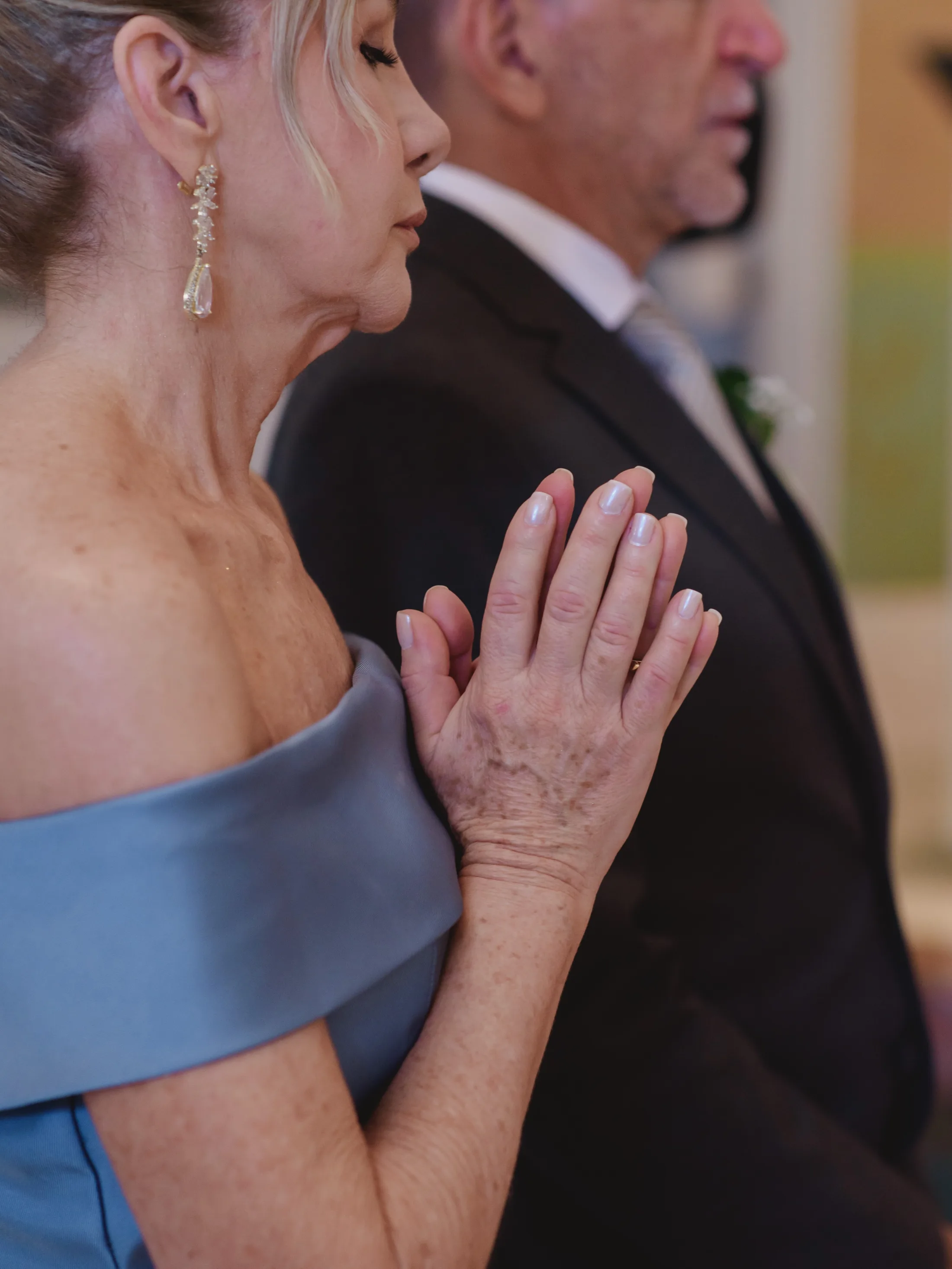 Casal de convidados com as mãos unidas durante a cerimônia.