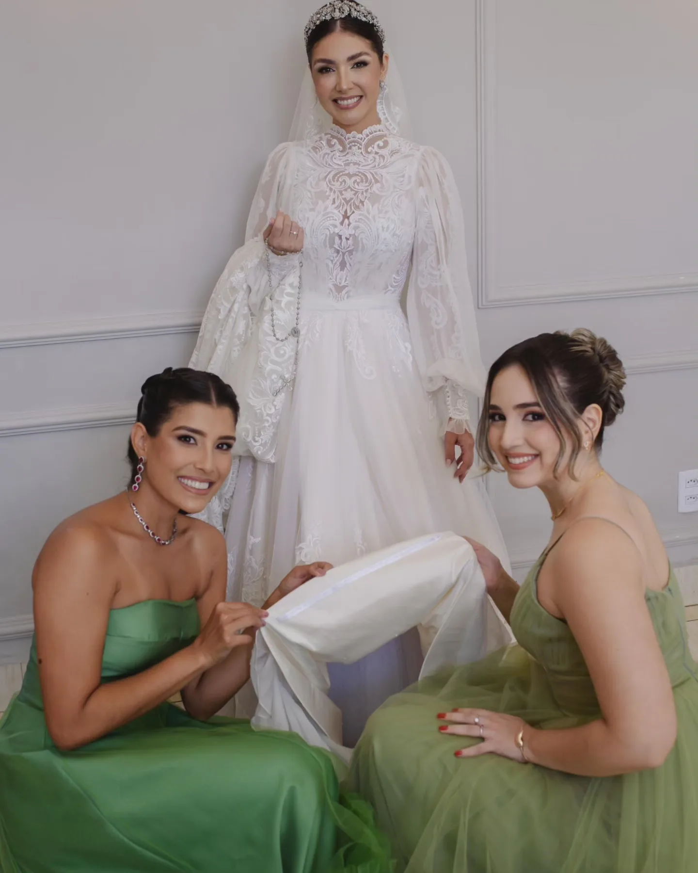 Noiva sentada ao lado de três mulheres de vestidos verdes.