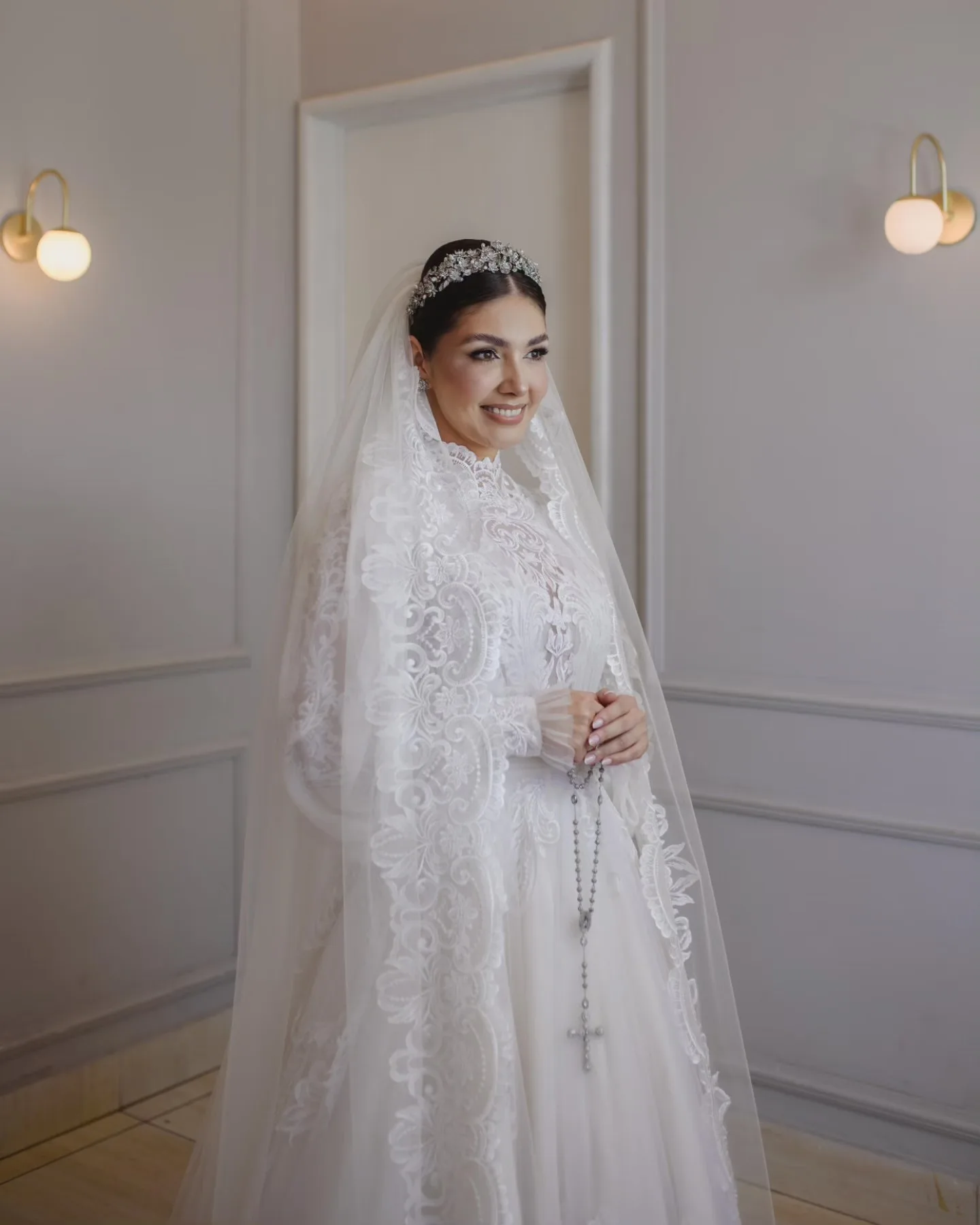 Noiva de véu, olhando para trás em uma sala clara.